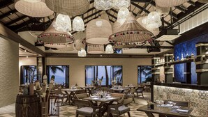 A restaurant with multiple tables, wicker hanging lamps, and a view of the ocean. - Samui Palm Beach Lead by Celes Samui (Koh Samui)
