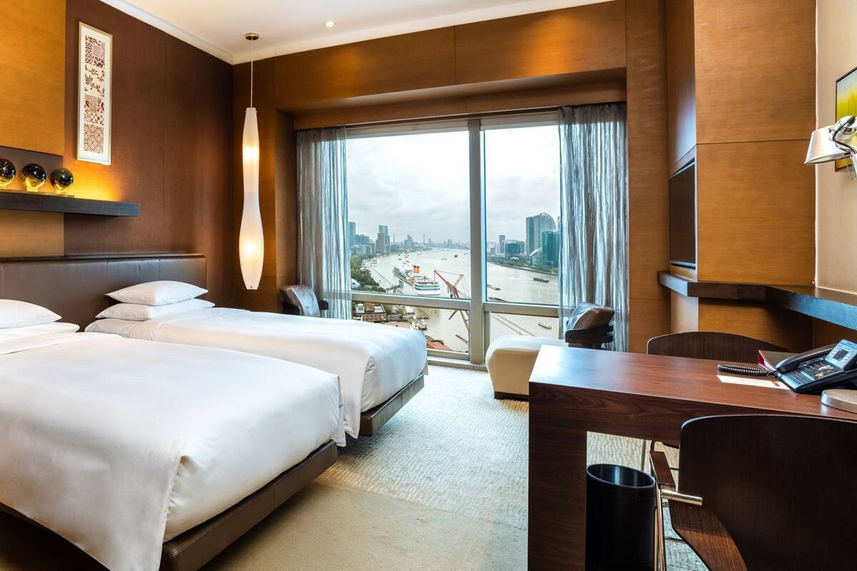 Camera d'albergo con due letti, una scrivania, una sedia, un telefono e vista sulla città.