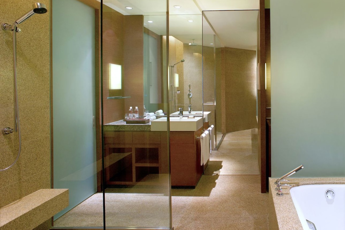 A modern bathroom with a glass partition, a shower, a sink, and a bathtub.
