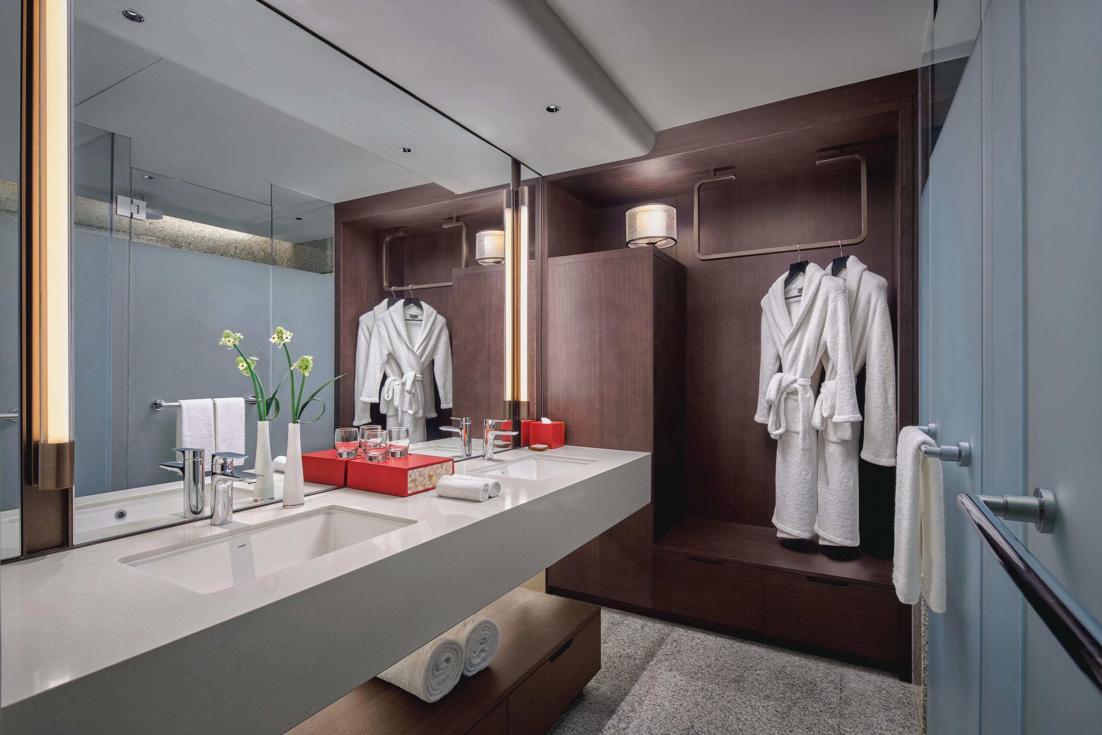 A modern bathroom with a large mirror, two sinks, and wooden paneling.
