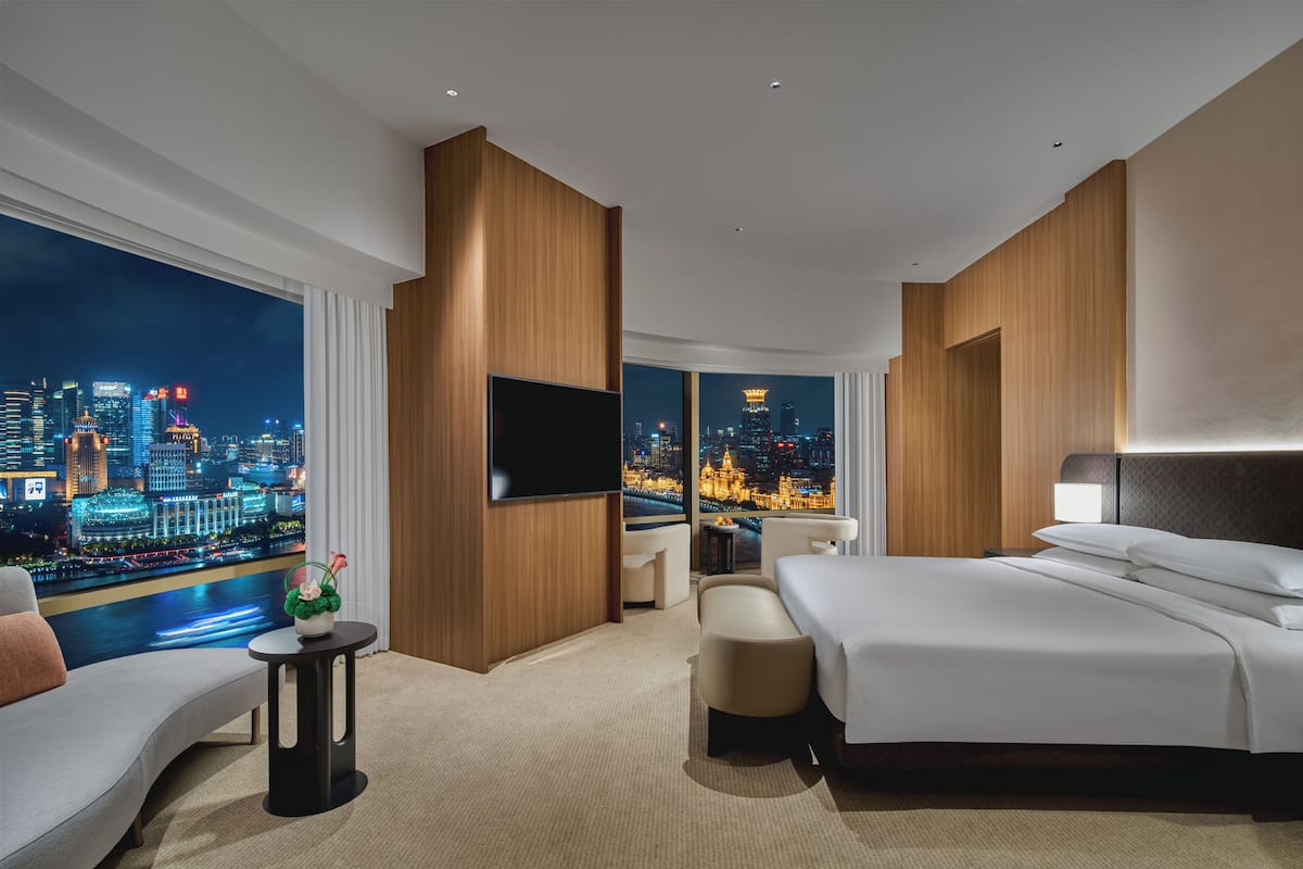 Una moderna camera d'albergo con un letto grande, una poltrona, una televisione e vista sulla città.