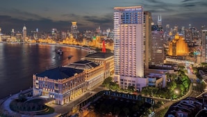 A high-rise hotel with a modern design, located near a waterfront with a river and city skyline in the background. - Hyatt on the Bund, Shanghai (Shanghai)
