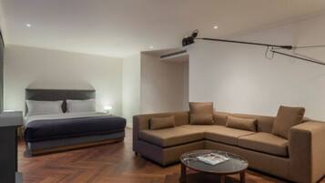 A modern hotel room with a bed, a sofa, a coffee table, and a ceiling-mounted projector.