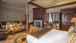 A spacious bedroom with a large bed, a four-poster canopy, a fireplace, and a sitting area with sofas and armchairs. - The Roseate Reading (Reading)