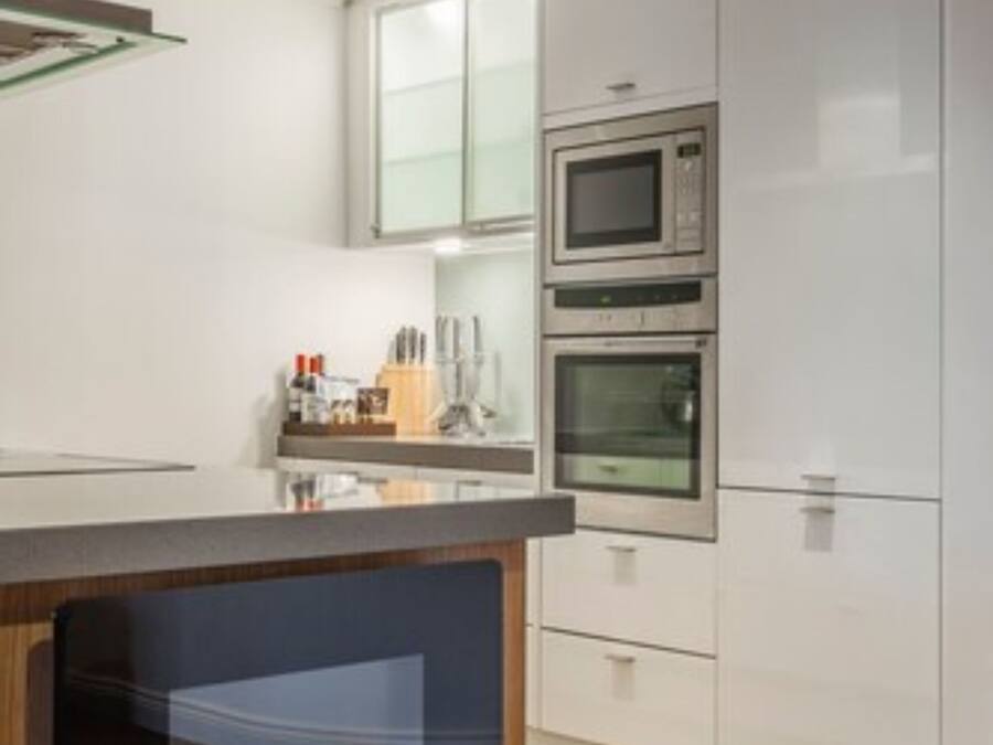 Une cuisine moderne dotée d’une cheminée intégrée, de meubles blancs et d’un four à micro-ondes placé au-dessus du plan de travail.