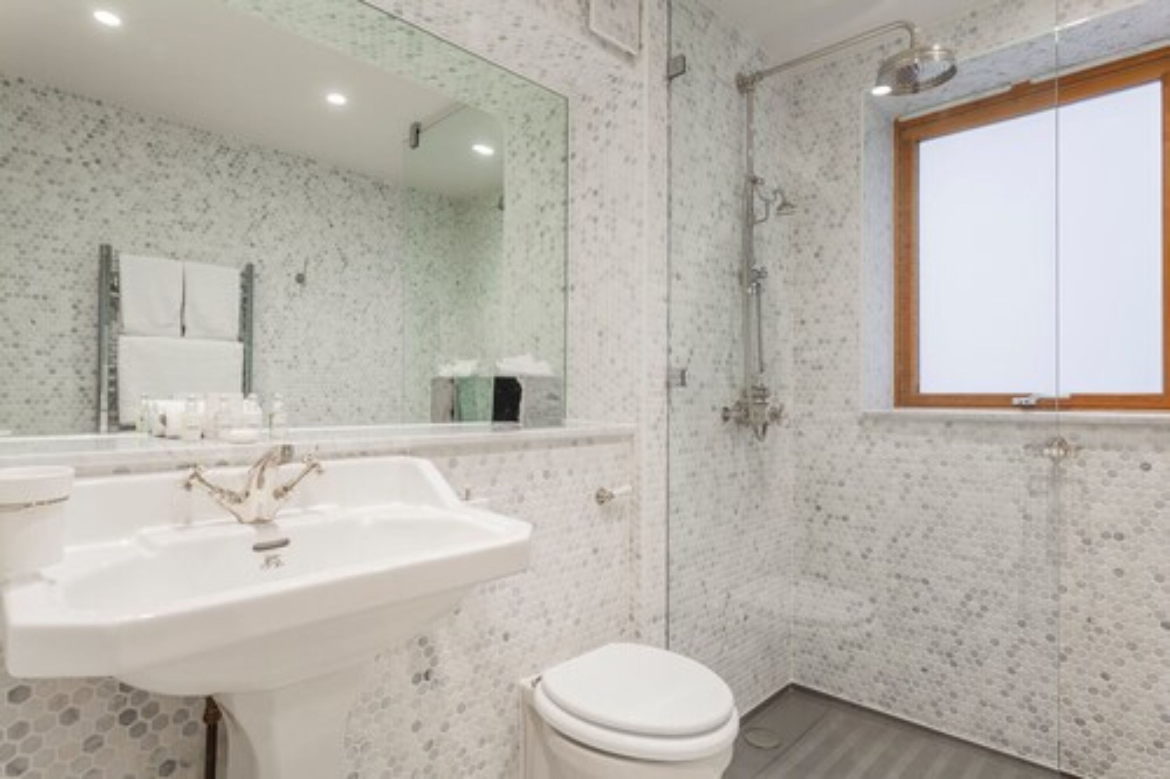 A bathroom with a white sink, a toilet, a shower, and a large mirror.