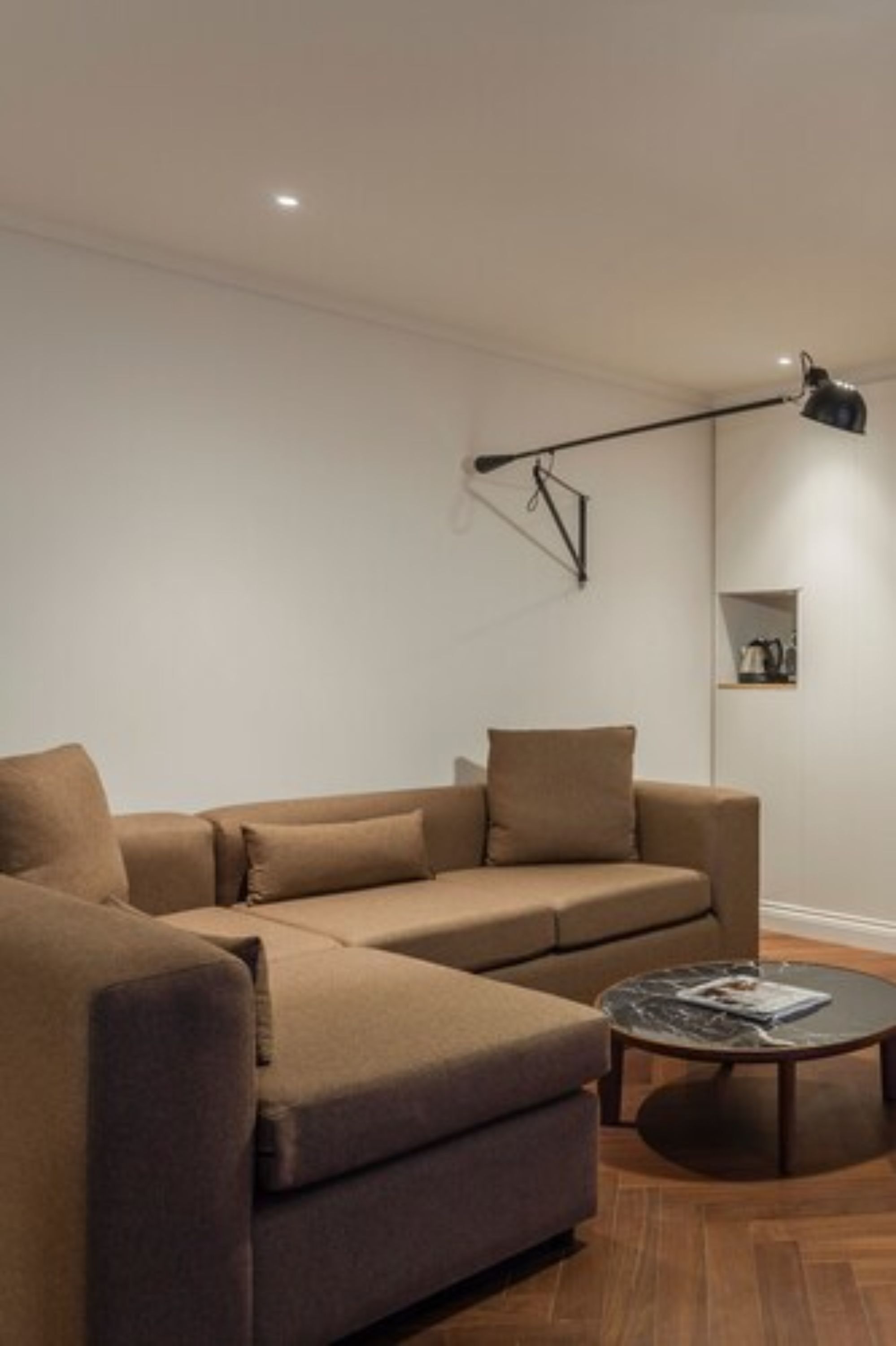 A modern living room with a sectional sofa, a round coffee table, and a wall-mounted floor lamp.