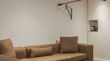 A modern living room with a sectional sofa, a round coffee table, and a wall-mounted floor lamp.