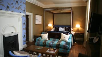 Un dormitorio con una cama con dosel, chimenea, sofá y televisor.