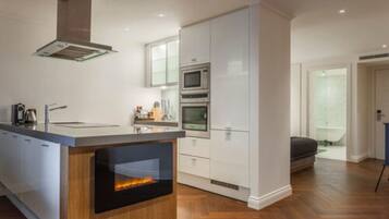 A modern kitchen with a central island, built-in ovens, and a wood-burning stove.