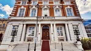 A historic building with a prominent entrance, a sign reading "THE ROSEATE," and a symmetrical facade with multiple windows and a central door.