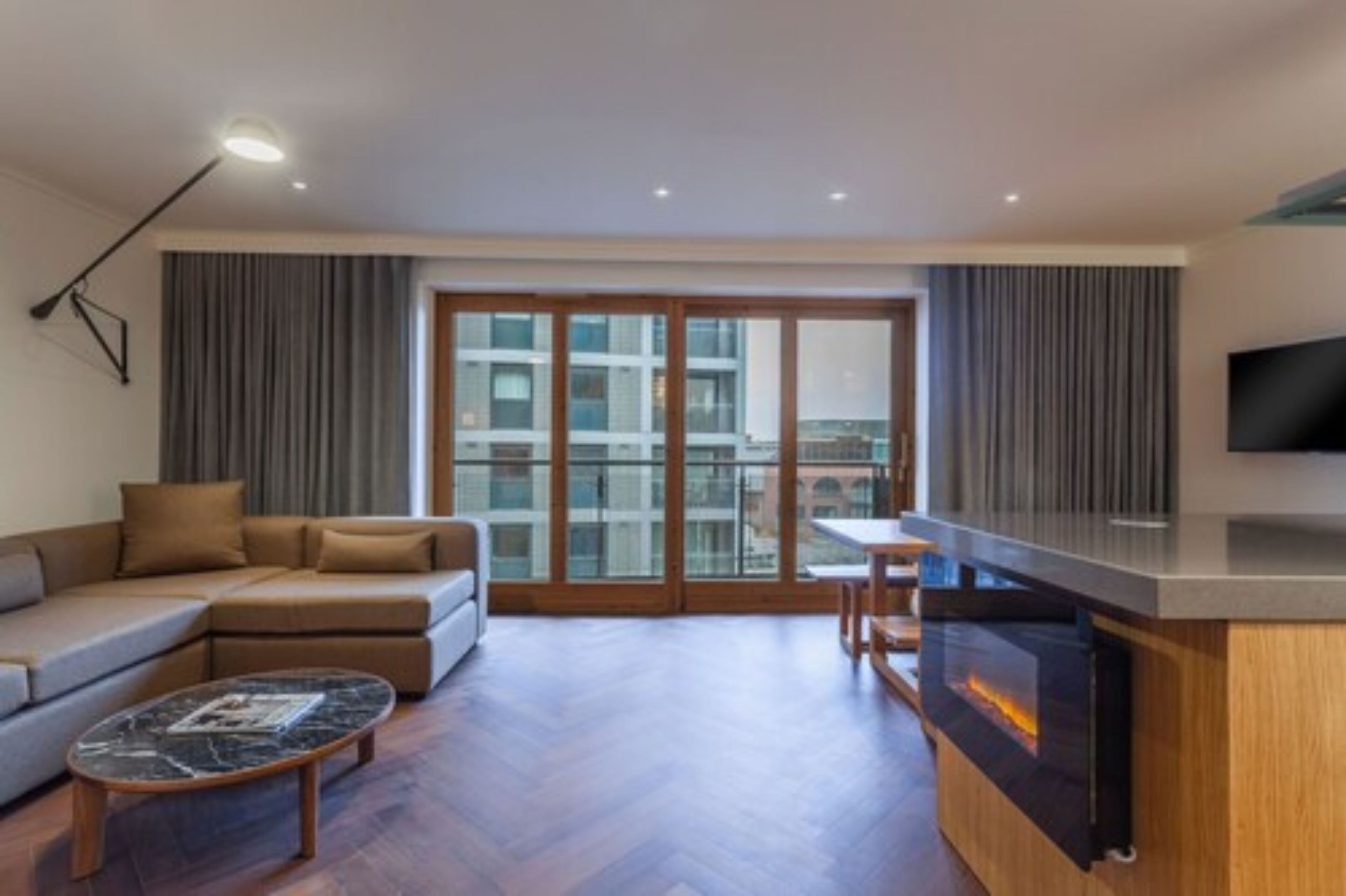 A modern living room with a sofa, a coffee table, a fireplace, and a TV.