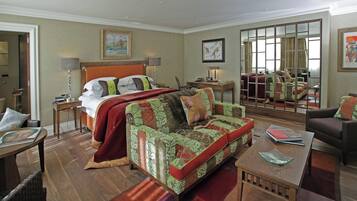Una habitación de hotel con cama, sofá, mesa de centro, escritorio y espejo.
