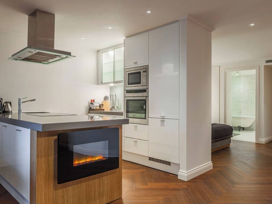 A modern kitchen with a central island, built-in oven, microwave, and a glass range hood.