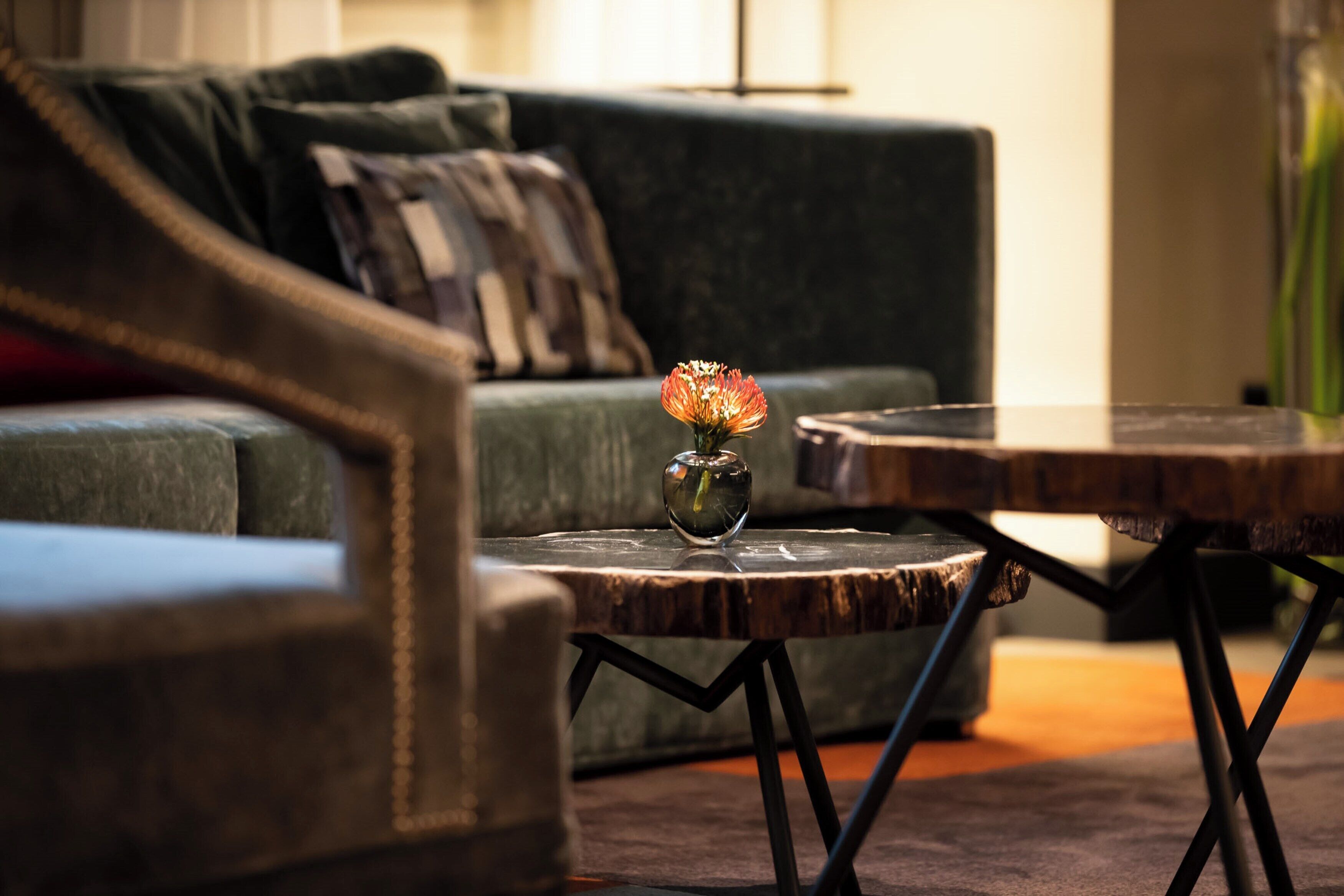 A living room with a sofa, a coffee table, and a vase with a flower.
