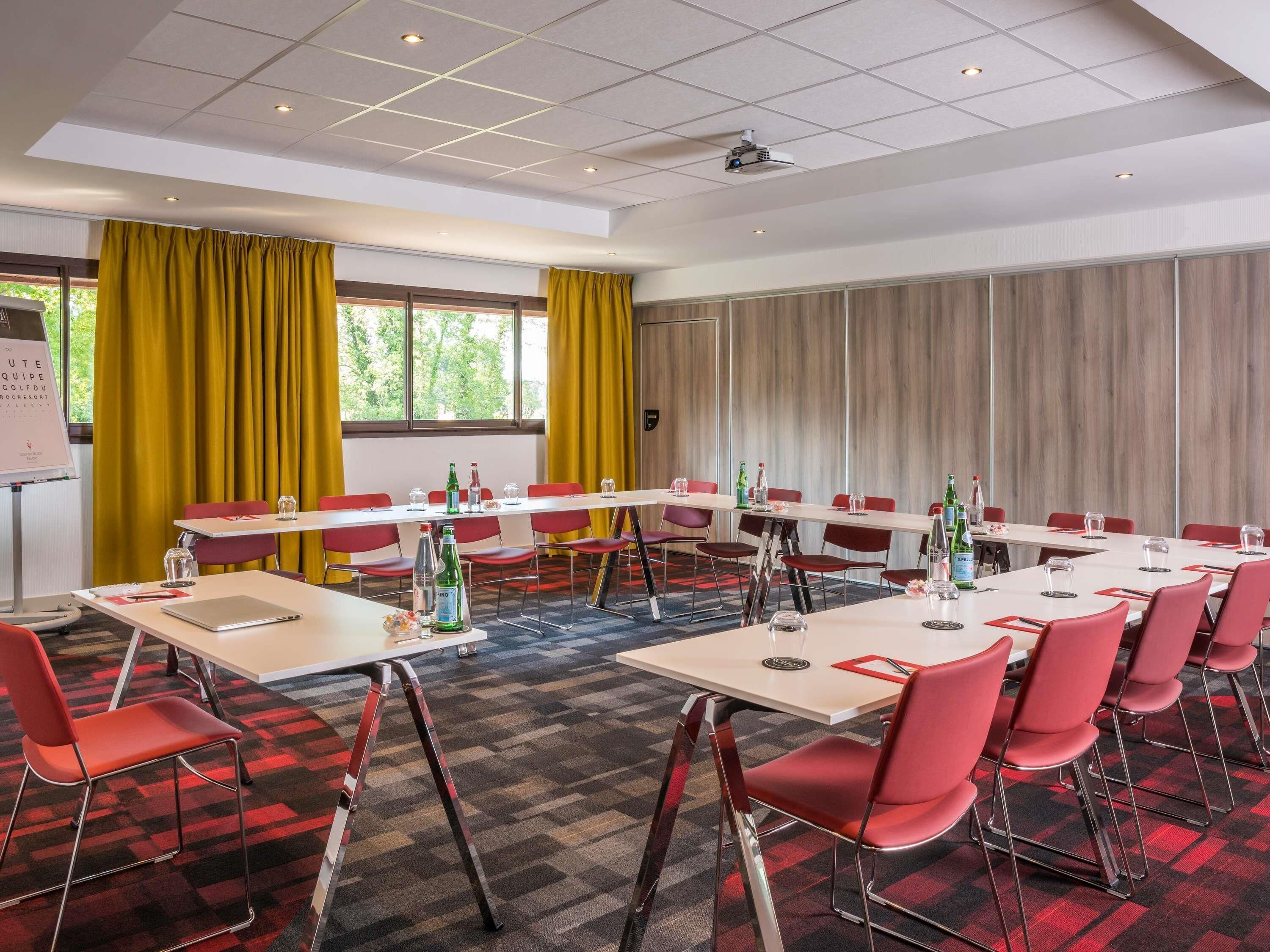 A conference room with tables, chairs, and a projector.