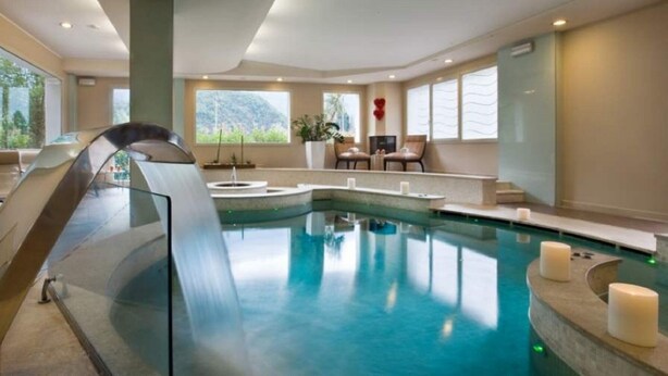 A modern indoor pool with a glass barrier, seating area, and large windows. - Rizzi Aquacharme Hotel & Spa (Darfo Boario Terme)