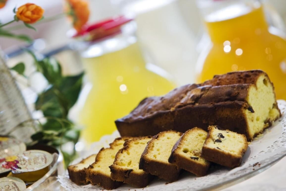 A loaf of cake with slices on a plate, set against a yellow background with blurred floral decorations.
