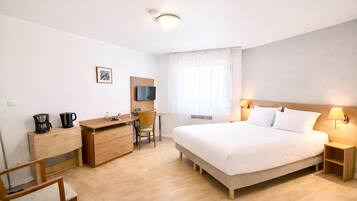 A hotel room with a bed, desk, chair, and a television.