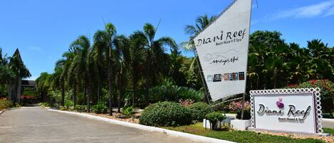 A sign for Diani Reef Beach Resort & Spa with a clear view of the surrounding palm trees and greenery.
