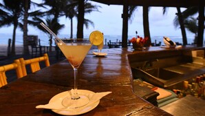 A bar table with a cocktail, palm trees, and a view of the beach. - Diani Reef Beach Resort & Spa - Your Beachfront Bliss Awaits (Diani Beach)