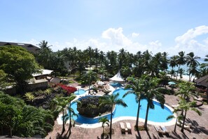 A resort with a central swimming pool surrounded by palm trees and lounge chairs. - Diani Reef Beach Resort & Spa - Your Beachfront Bliss Awaits (Diani Beach)