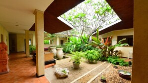 A spacious courtyard with a tiled floor, potted plants, and a large tree providing shade. - Diani Reef Beach Resort & Spa - Your Beachfront Bliss Awaits (Diani Beach)