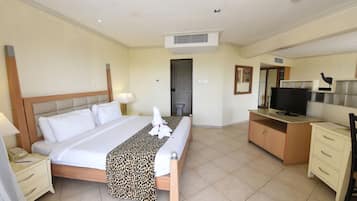 Habitación de hotel con una cama grande, un escritorio con televisor, un armario y la puerta del baño.