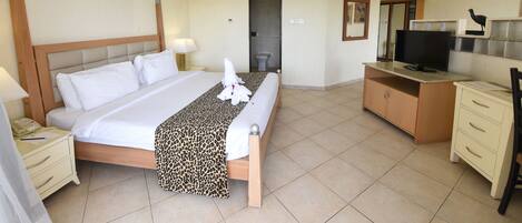 A hotel room with a large bed, a desk with a TV, a wardrobe, and a bathroom door.