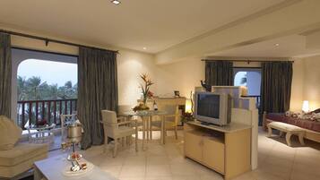 A hotel room with a balcony, a dining area, a TV, a bed, and a sofa.