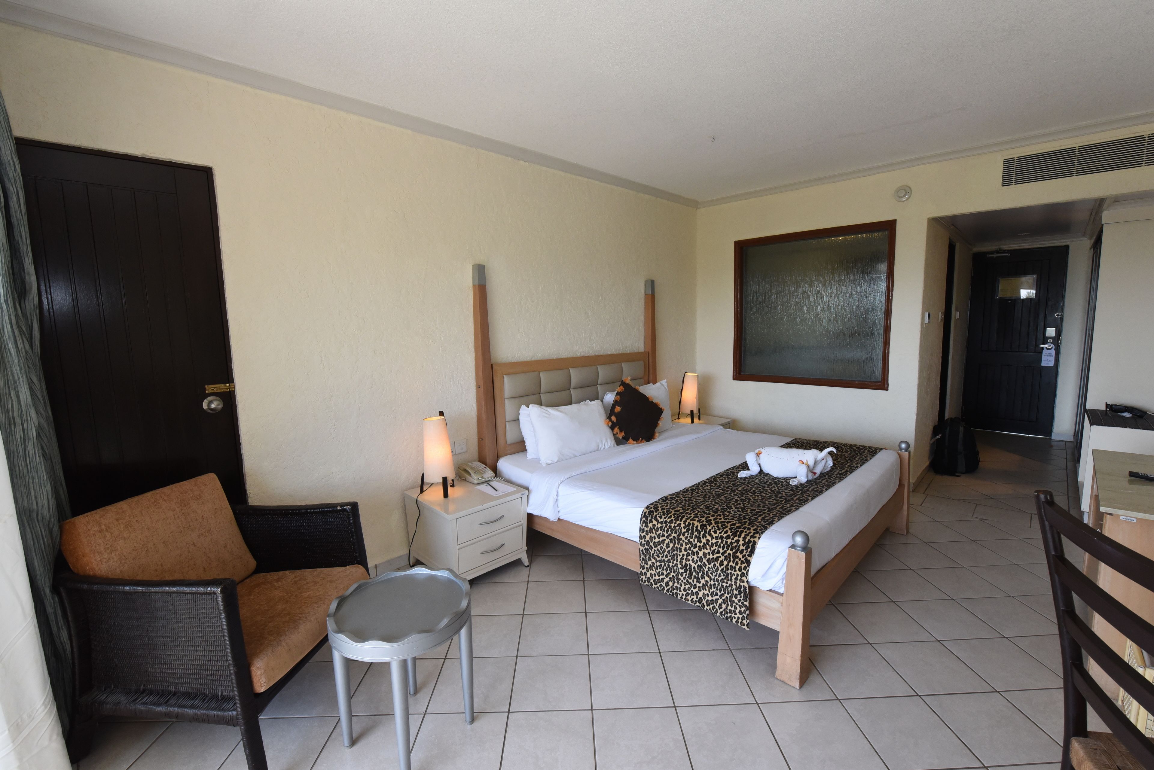 A hotel room with a bed, bedside tables, a chair, and a desk.