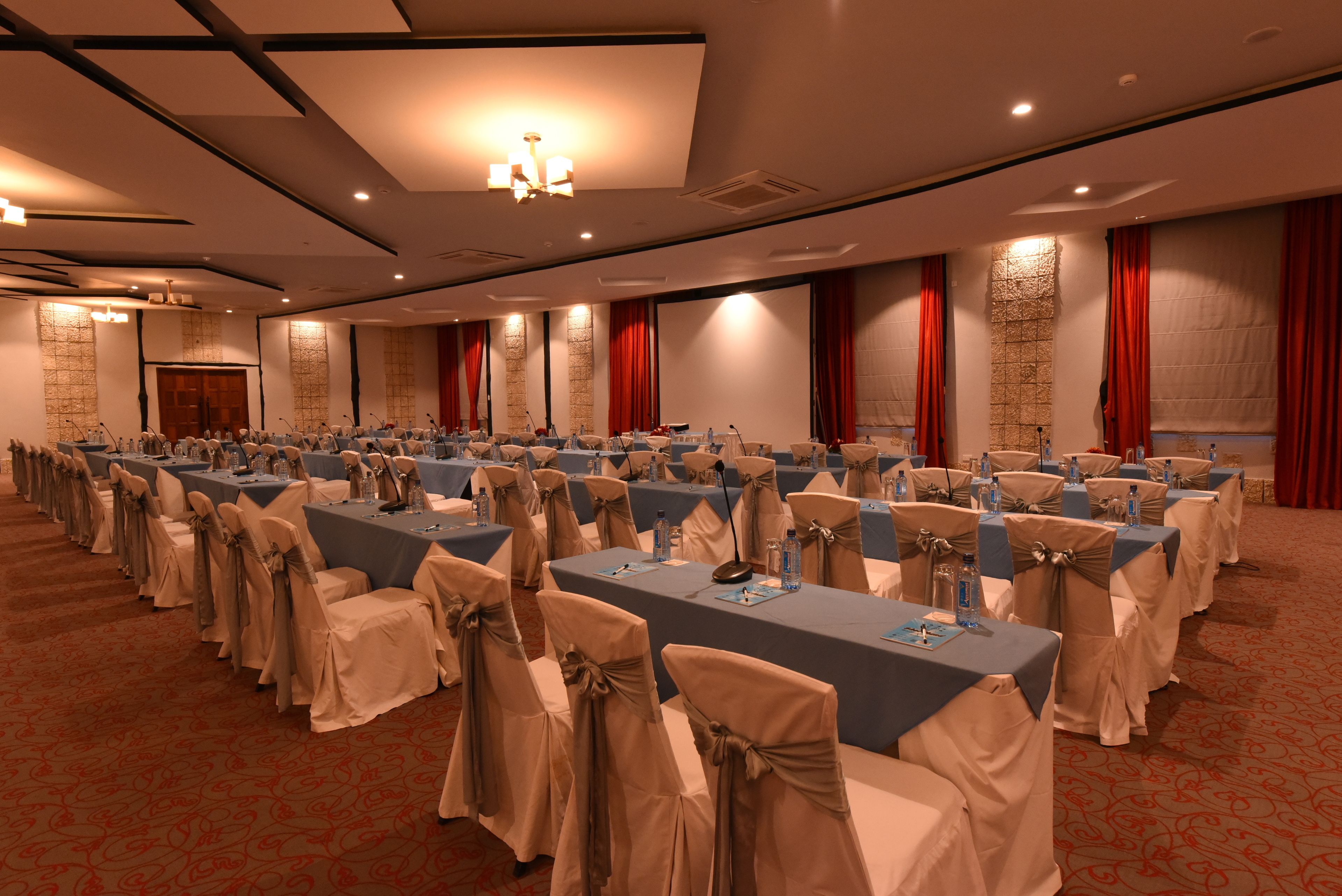 A conference room with rows of tables, chairs, and microphones, indicating a formal meeting setup.