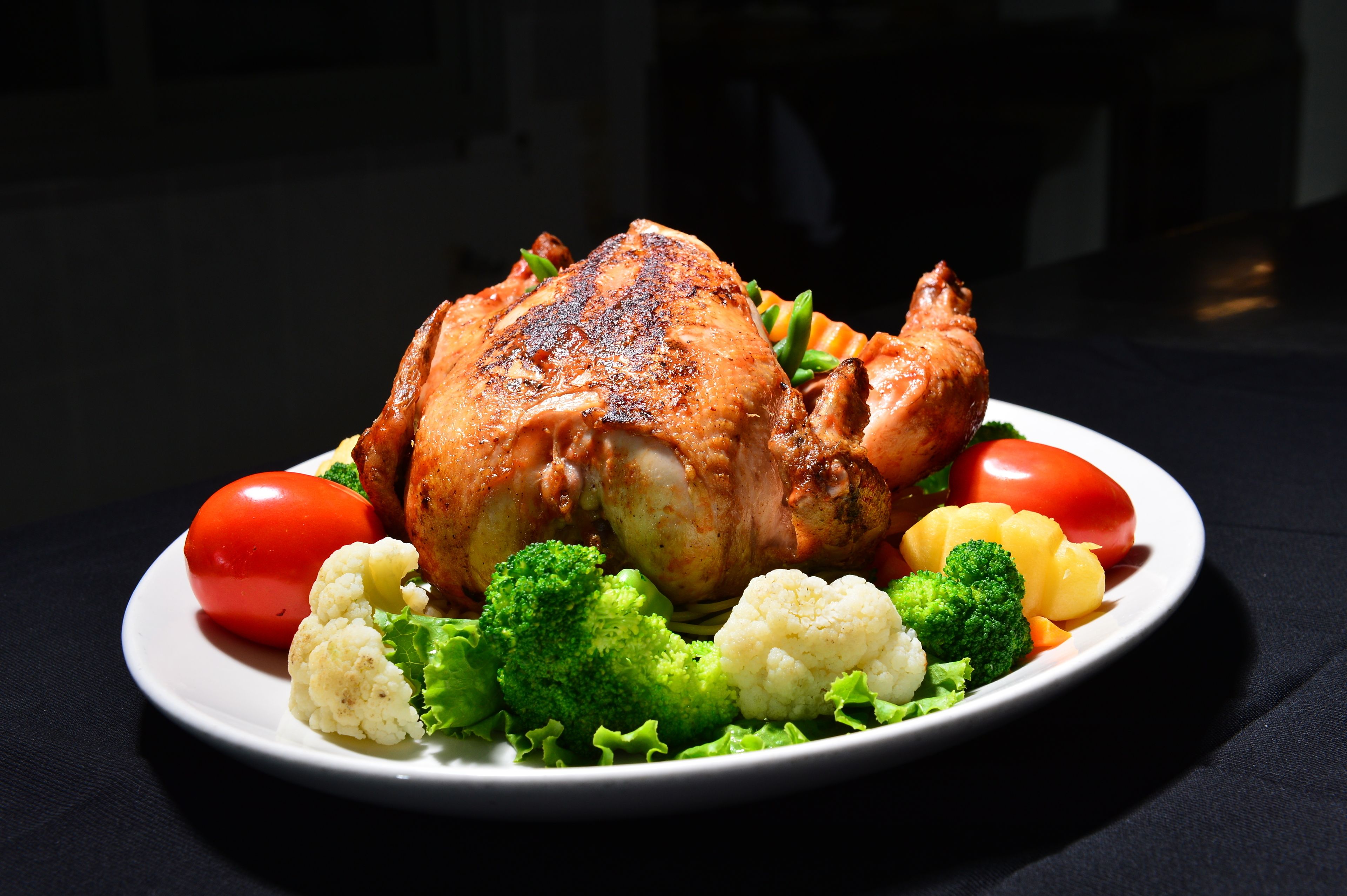 A roasted chicken with vegetables on a plate.