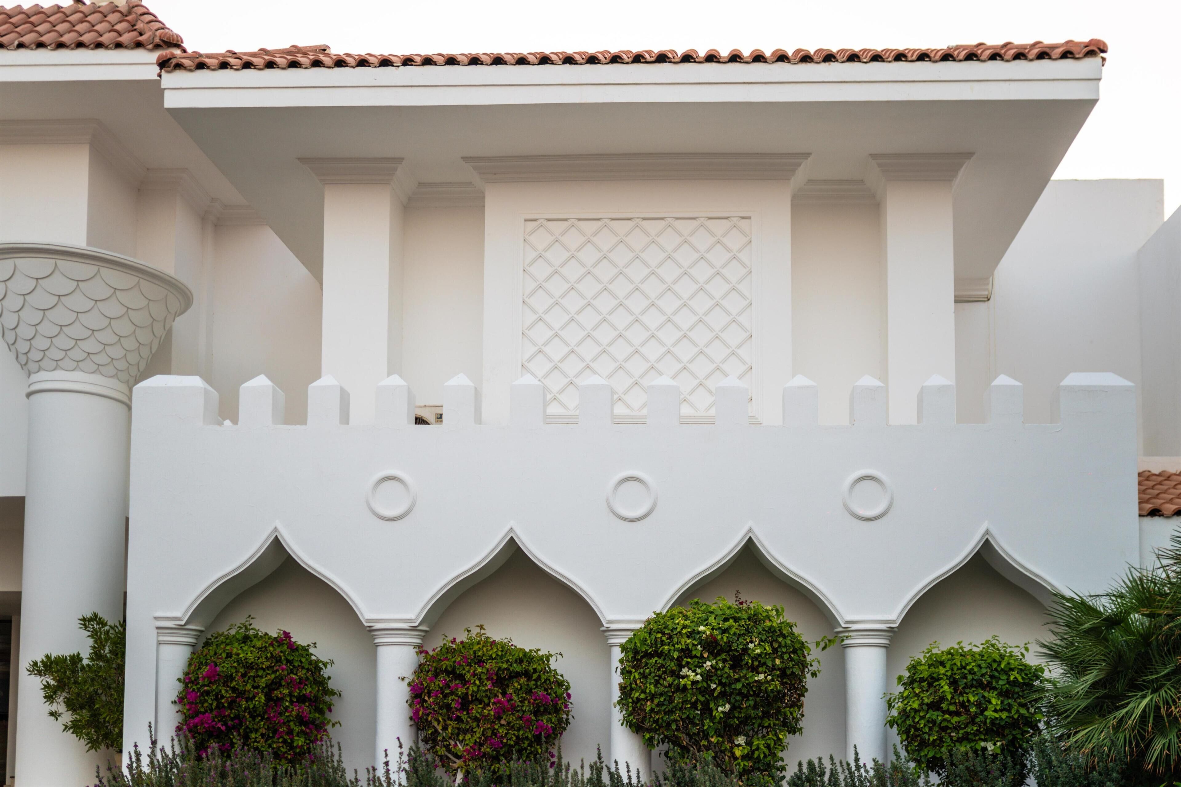 A building with white walls, a tiled roof, and decorative arches.