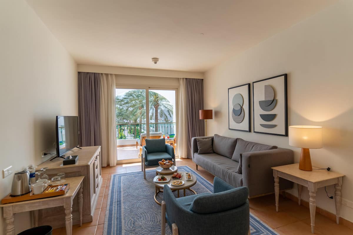 A modern living room with a sofa, armchairs, a coffee table, and a TV.