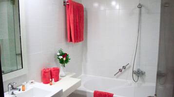 Un bagno con lavandino bianco, uno specchio e una doccia con soffione manuale.