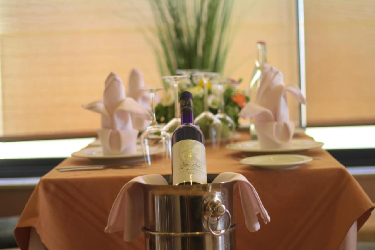 Een eettafel gedekt met een fles wijn, glazen en een bloevas.