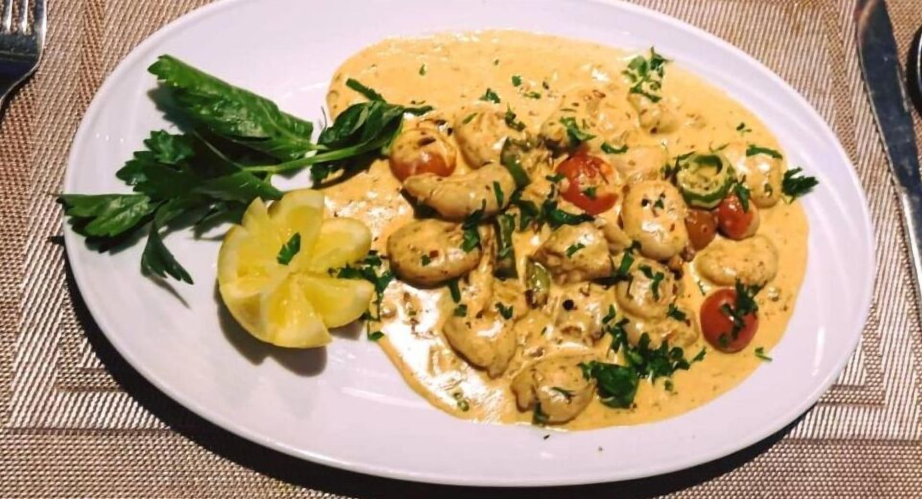 Un plato de comida con salsa cremosa, adornado con hierbas y verduras.