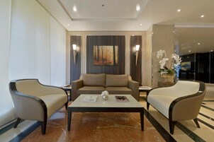 Un moderno hall de hotel con un conjunto de sofás, dos sillones, una mesita de centro y un cuadro en la pared.