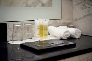 Uma bancada de banheiro com produtos de higiene, incluindo frascos e uma toalha.