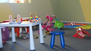 A playroom with a table, stools, a small slide, and various toys. - Monreal (San Michele All'adige)
