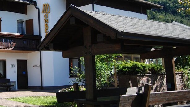 A hotel with a balcony, outdoor seating, and a wooden pergola. - Monreal (San Michele All'adige)