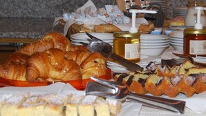 A buffet table with various pastries, including croissants and cakes, and condiments like honey and jam. - Monreal (San Michele All'adige)