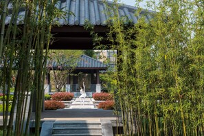 A traditional Japanese building with a tiled roof, surrounded by bamboo and flowering shrubs. - Jinling Riverside Hotel Nanjing (Nanjing)