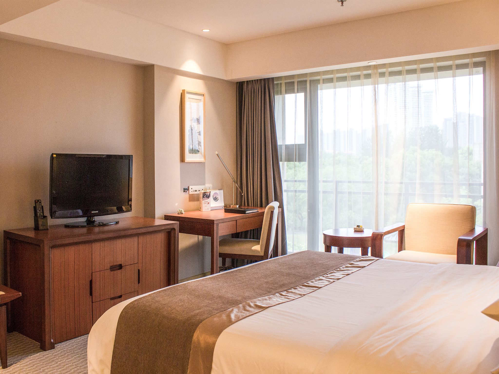 A hotel room with a bed, a desk with a computer, a television, and a chair.