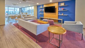 A modern lounge area with sofas, a coffee table, and a TV mounted on a wooden wall. - City Express by Marriott Toluca (Toluca)