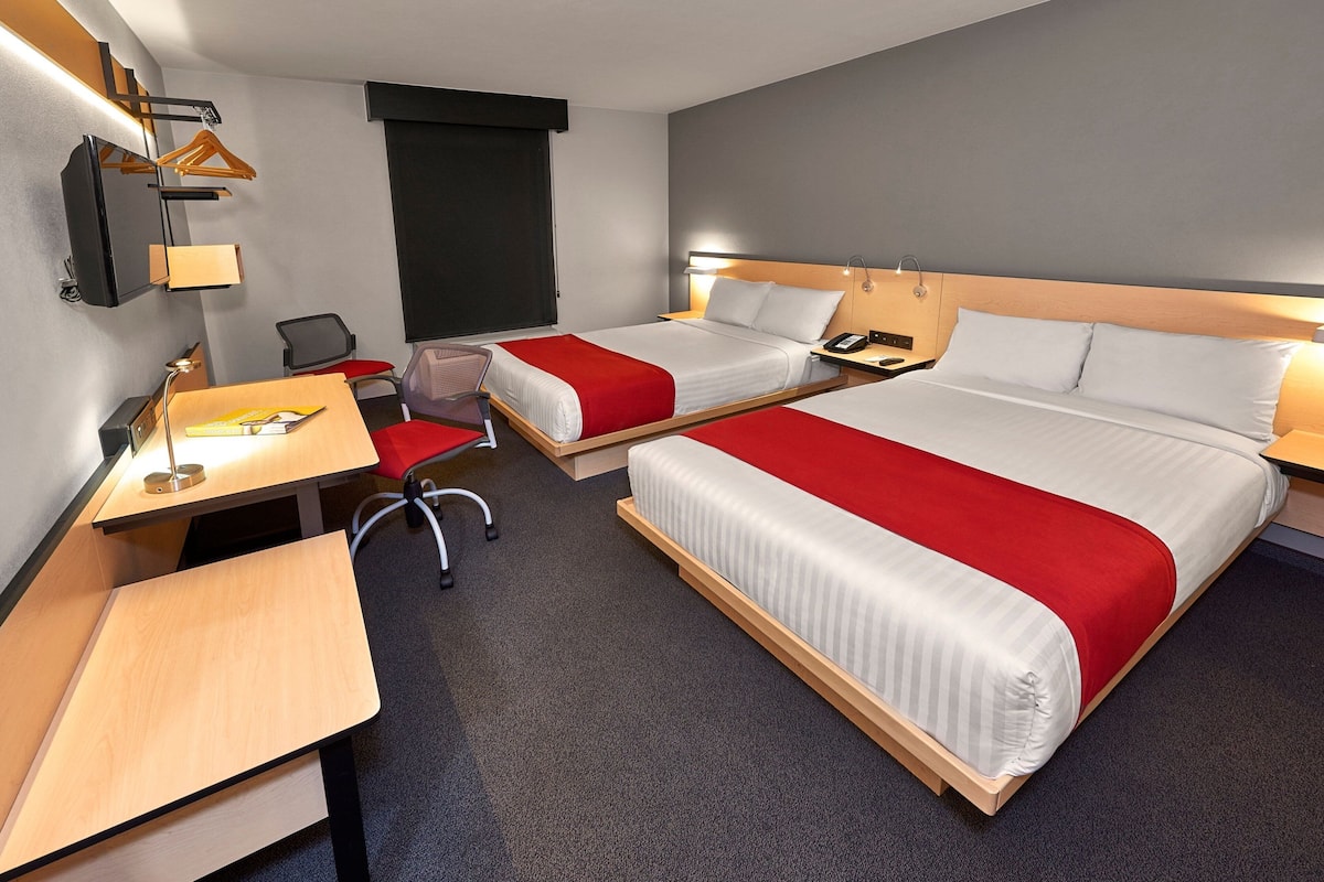 Une chambre d’hôtel avec deux lits, un bureau, une chaise et un téléviseur.