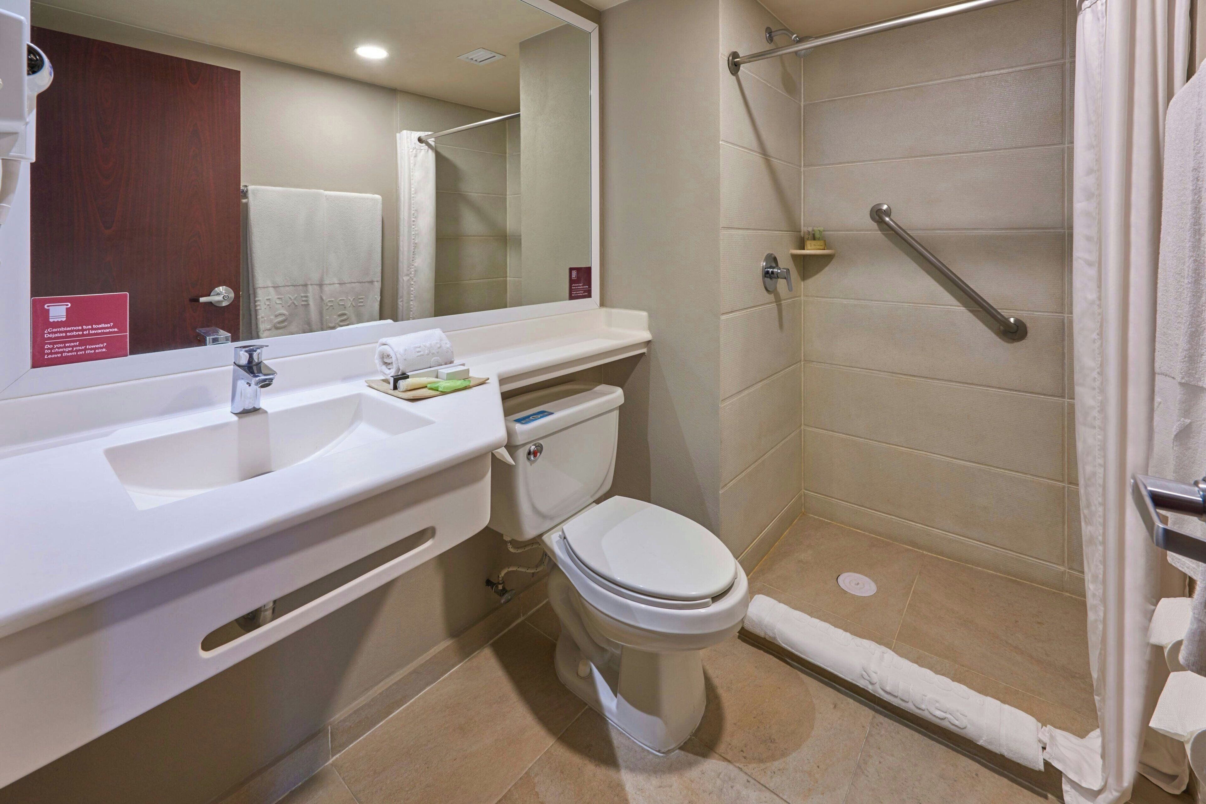 Un baño con lavamanos, inodoro y ducha blancos.