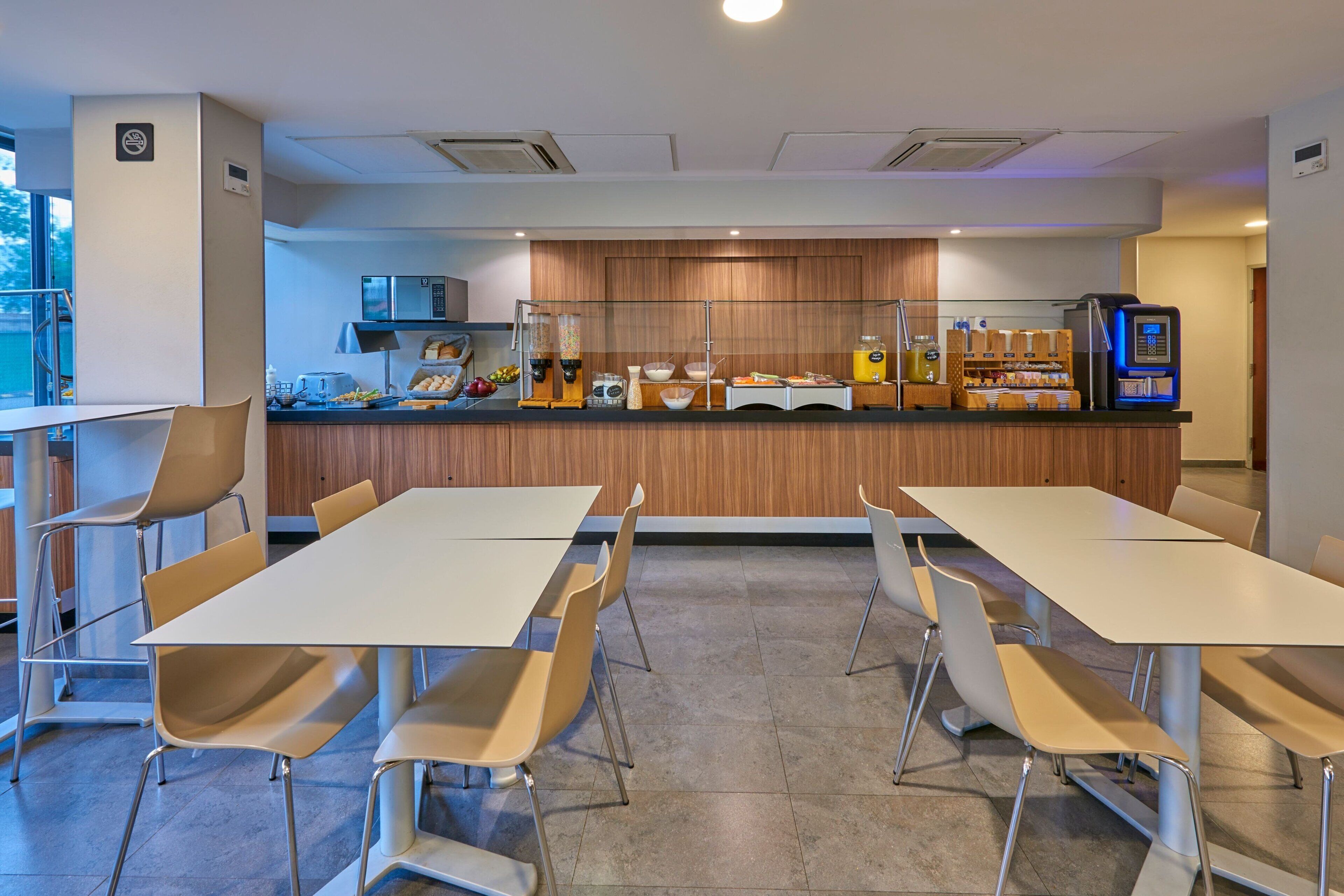 A modern café with a long counter, multiple tables, and chairs.