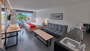 A modern hotel room with a bed, sofa, dining table, and kitchenette. - City Express by Marriott Tampico (Tampico)